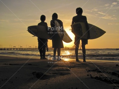 Fair Trade Photo Activity, Backlit, Beach, Colour image, Evening, Friendship, Good luck, Group of boys, Horizontal, Low angle view, Outdoor, People, Peru, Reflection, Sea, Silhouette, South America, Sport, Standing, Surf, Surfboard, Water