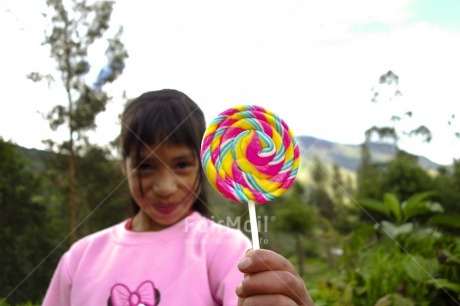 Fair Trade Photo Activity, Birthday, Colour image, Day, Focus on foreground, Giving, Horizontal, Lollypop, Looking at camera, Multi-coloured, One girl, Outdoor, People, Peru, Portrait halfbody, Smiling, South America