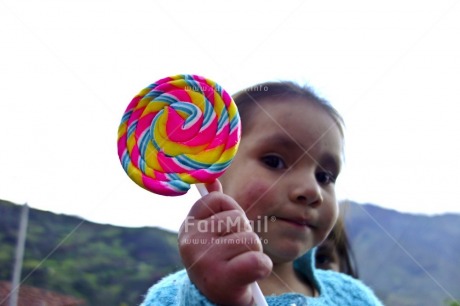 Fair Trade Photo 5 -10 years, Activity, Colour image, Day, Giving, Horizontal, Latin, Lollypop, Looking away, Multi-coloured, One child, One girl, Outdoor, People, Peru, Portrait headshot, South America, Sweets