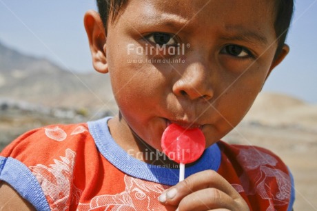 Fair Trade Photo 5 -10 years, Activity, Casual clothing, Clothing, Colour image, Day, Eating, Food and alimentation, Health, Horizontal, Latin, Lollypop, One boy, Outdoor, People, Peru, Portrait headshot, Red, South America