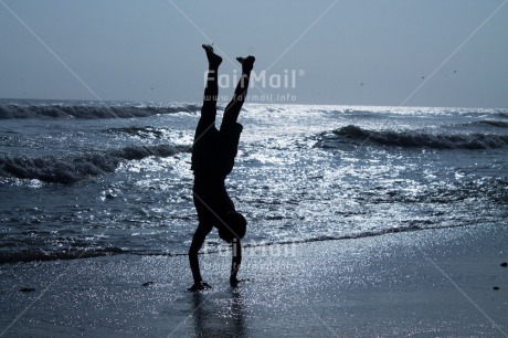 Fair Trade Photo Activity, Backlit, Beach, Colour image, Doing handstand, Emotions, Evening, Freedom, Happiness, One boy, Outdoor, People, Peru, Playing, Sea, Silhouette, Sky, South America, Sunset, Yoga