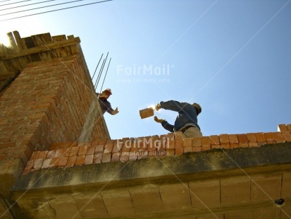 Fair Trade Photo Activity, Brick, Casual clothing, Clothing, Colour image, Construction, Cooperation, Day, Growth, Horizontal, Low angle view, Outdoor, People, Peru, Sky, South America, Streetlife, Throwing, Two men, Working