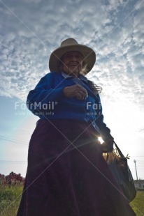 Fair Trade Photo Activity, Backlit, Blue, Clothing, Clouds, Evening, Grandmother, Latin, Light, Looking at camera, Low angle view, Old age, One woman, Outdoor, People, Portrait fullbody, Rural, Sky, Sombrero, Traditional clothing, Vertical