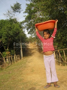 Fair Trade Photo 5 -10 years, Activity, Carrying, Casual clothing, Child labour, Clothing, Colour image, Day, Latin, Looking at camera, One girl, Outdoor, People, Peru, Portrait fullbody, Rural, Smiling, Social issues, South America, Tree, Vertical, Working